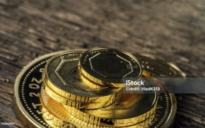 A few gold coins fineness 999.9 on a background of blurred wood texture.